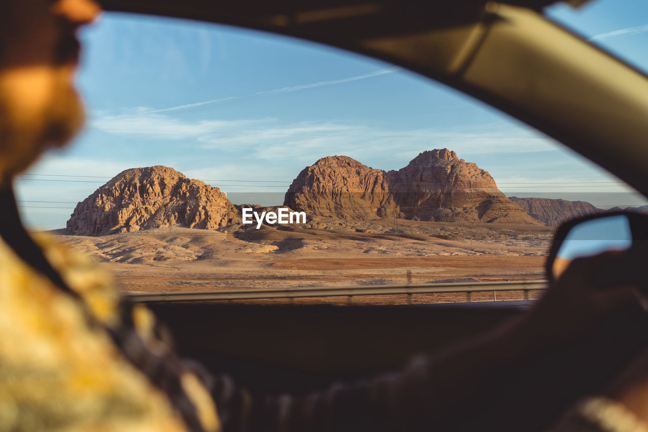 Close-up of man driving car with mountains seen through window