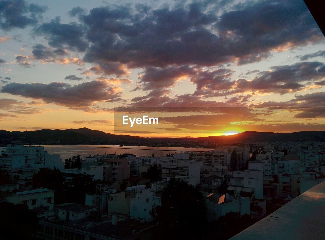 HIGH ANGLE VIEW OF TOWNSCAPE AGAINST ORANGE SKY