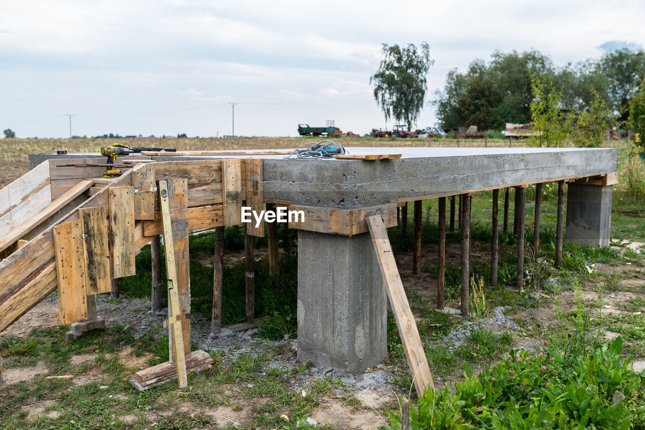 OLD WOODEN TABLE ON FIELD AGAINST SKY