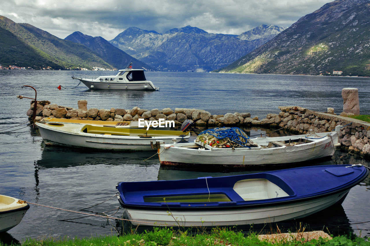 BOATS MOORED IN LAKE AGAINST MOUNTAIN