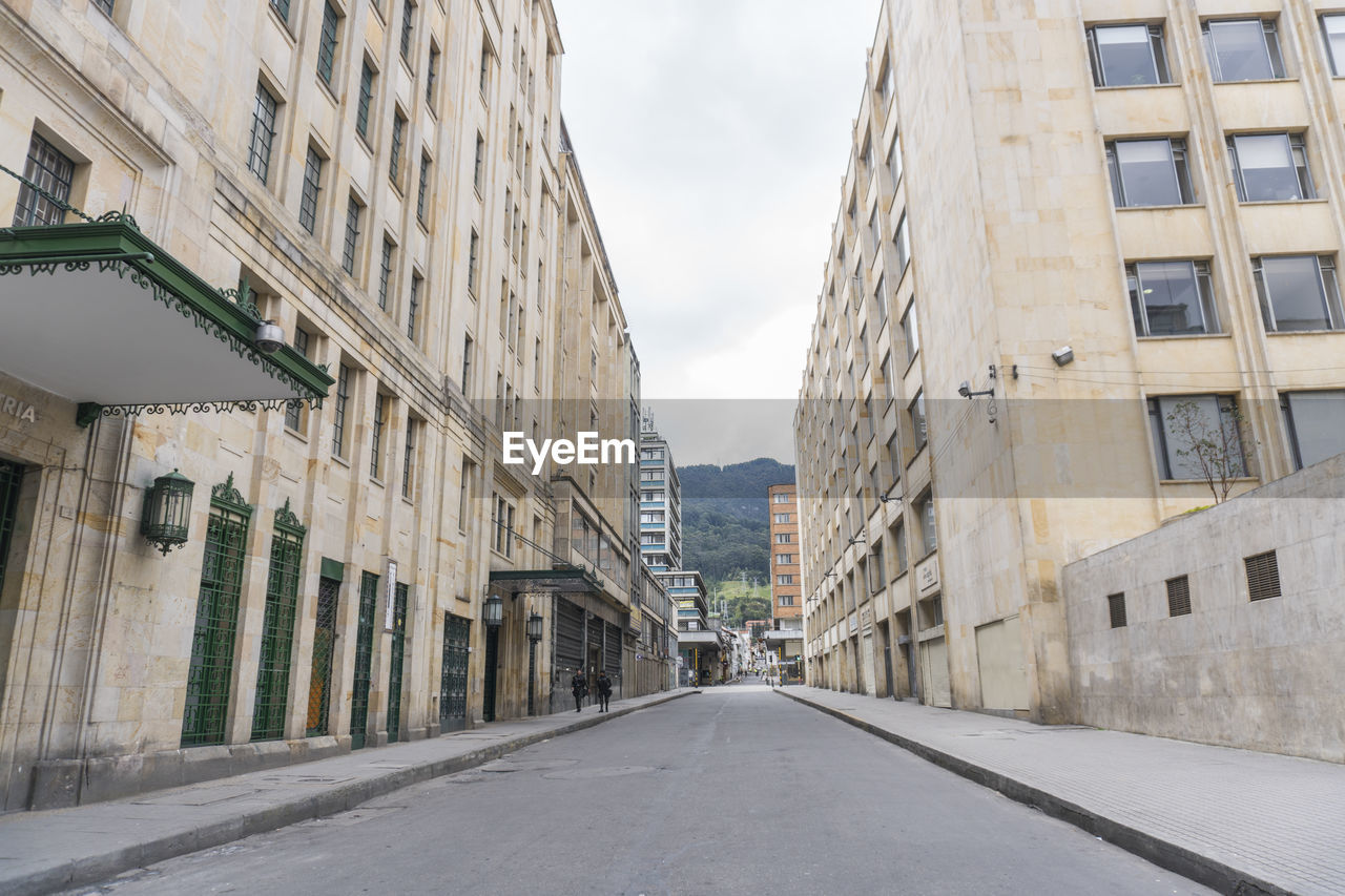 Empty road amidst buildings in city