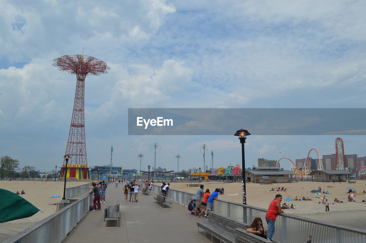 Group of people in amusement park against sky in coney island.
