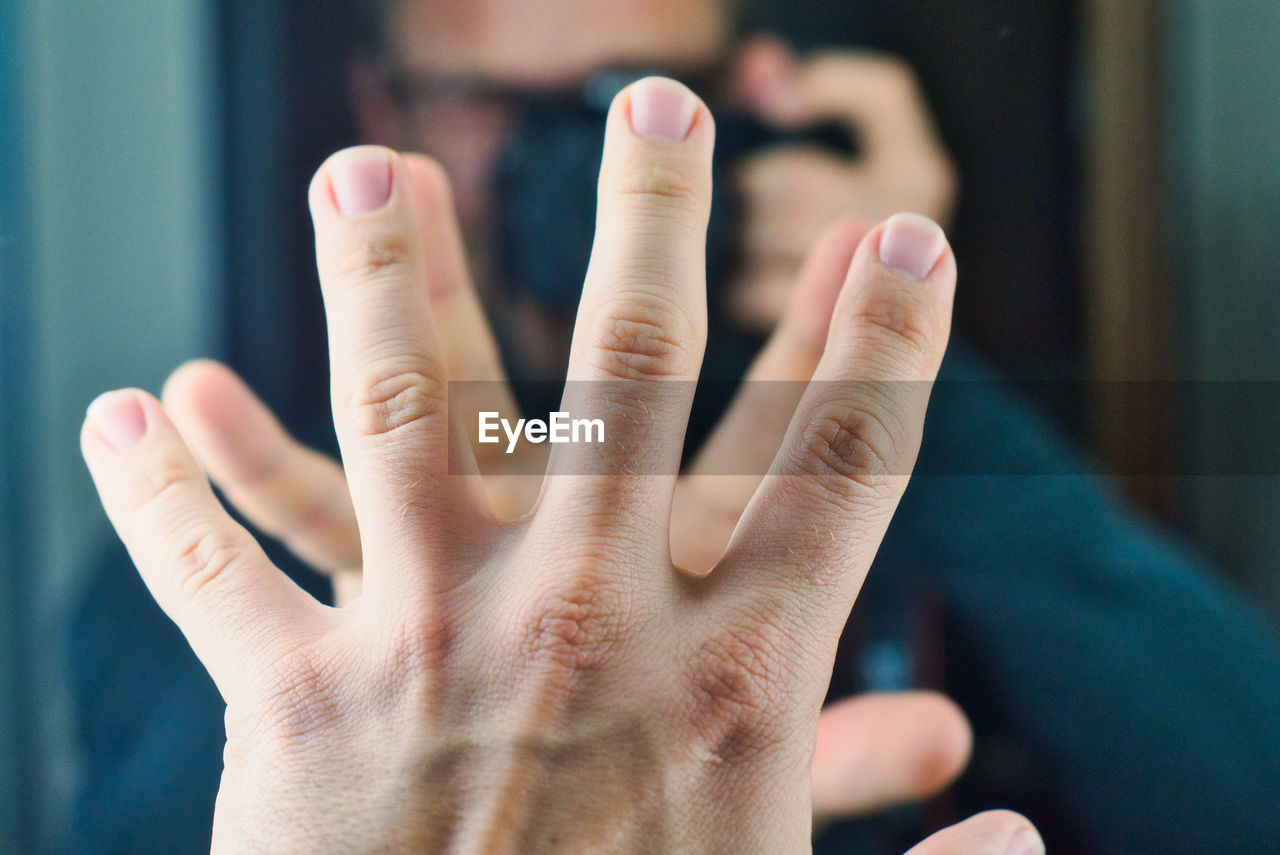 Cropped image of man reflecting while touching mirror indoors