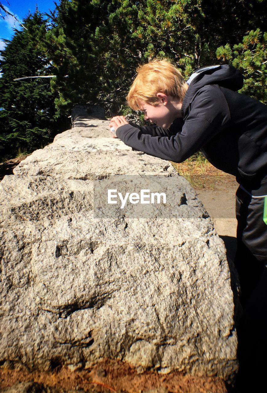 Side view of curious boy looking at retaining wall at crater lake national park