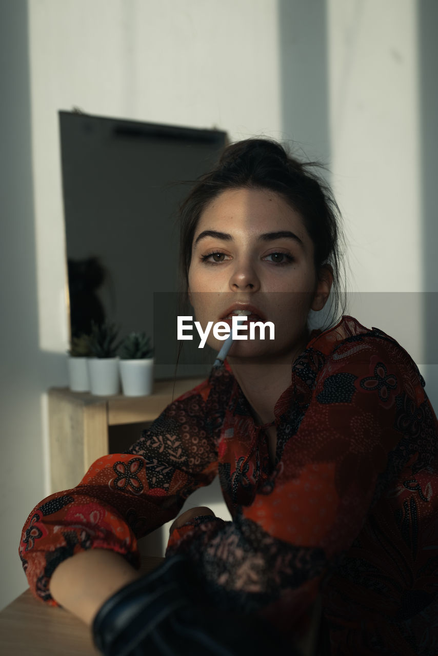 PORTRAIT OF A BEAUTIFUL YOUNG WOMAN HOLDING CAMERA