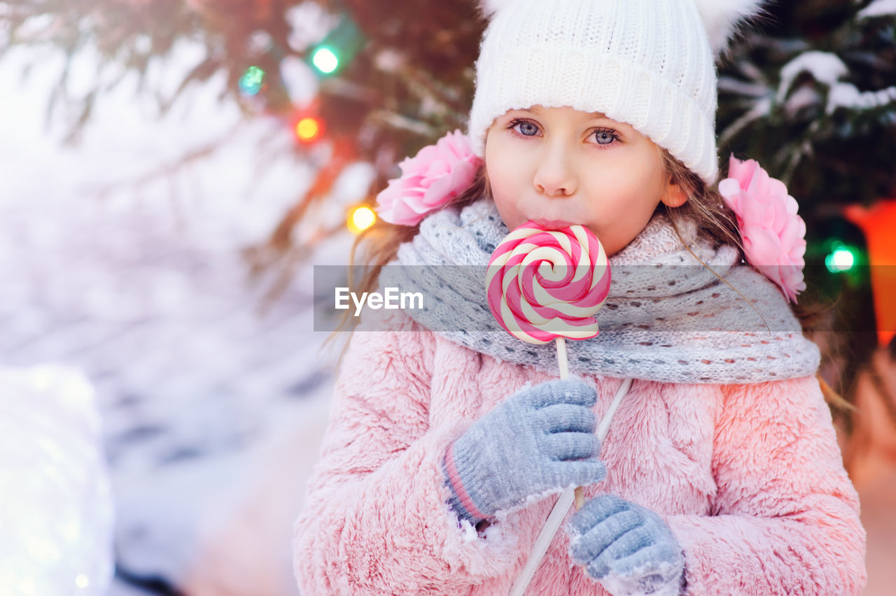 Portrait of cute girl eating candy during winter