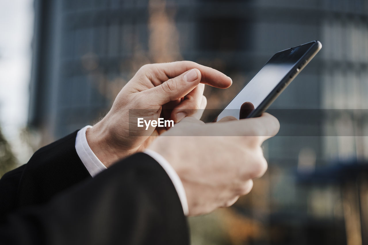 Close-up of businessman using smart phone outdoors