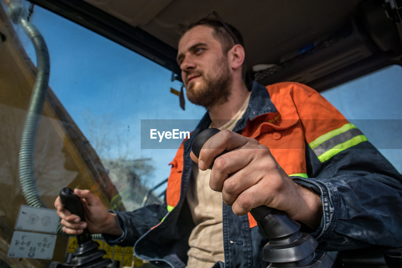 Low angle view of man working in excavator 