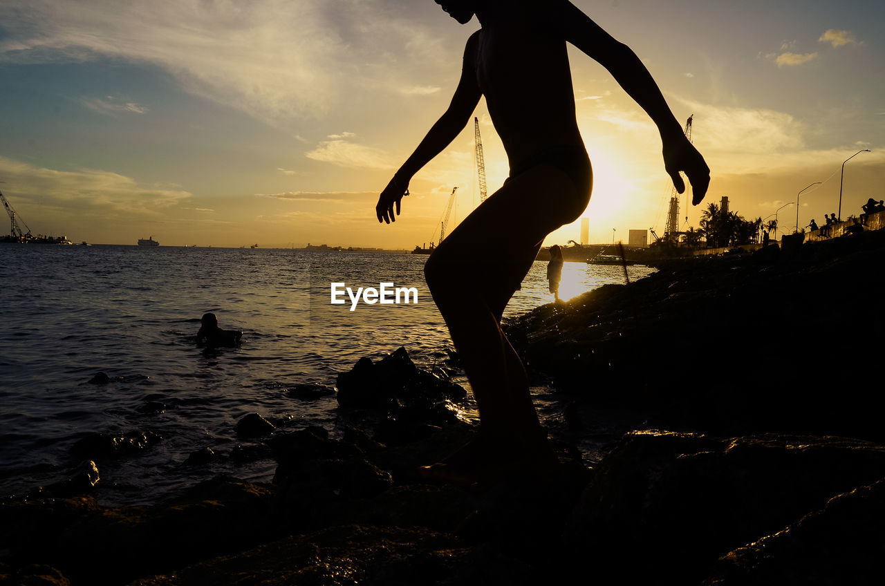 Silhouette people on beach against sky during sunset