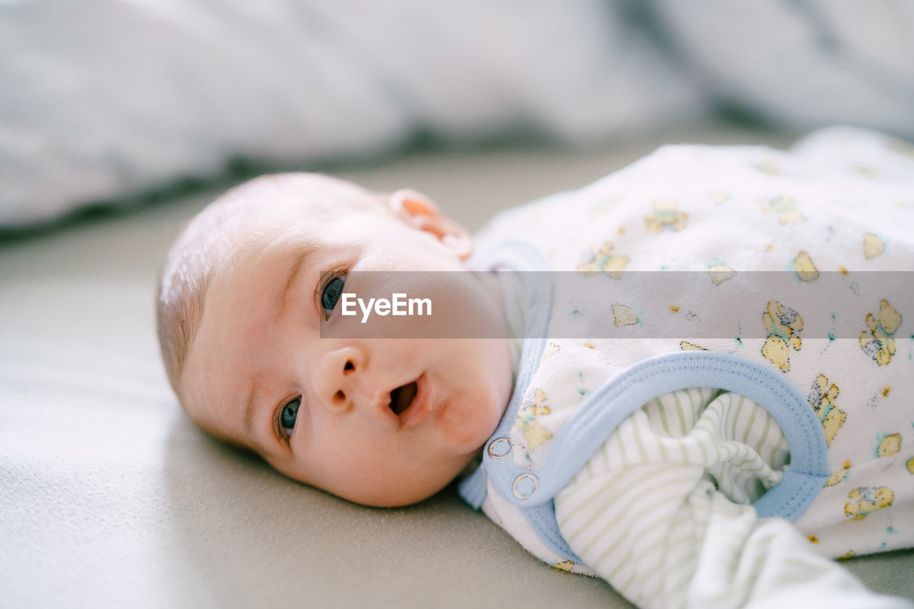 close-up of cute baby boy lying on bed at home