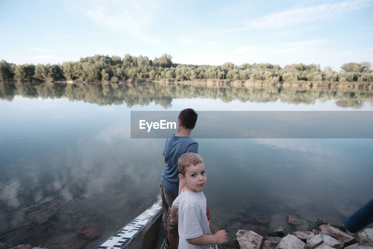 Full length of boys on lake against sky