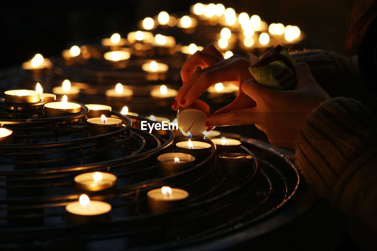 Cropped hands of woman lightning candles