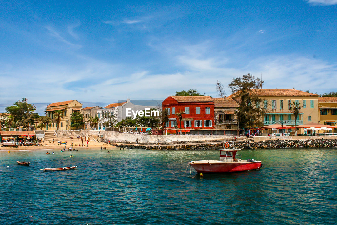 Boats in sea by buildings in city against sky