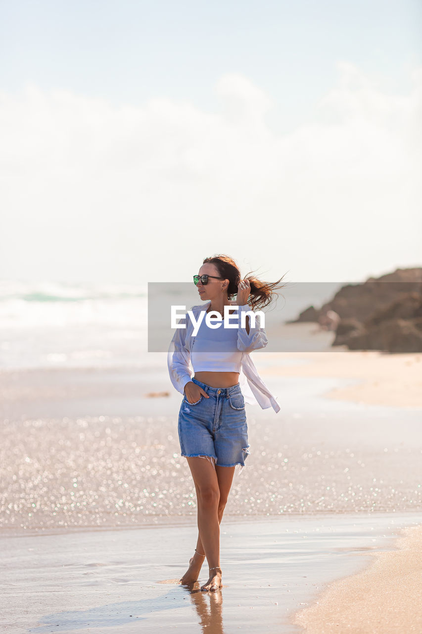 full length of young woman standing at beach