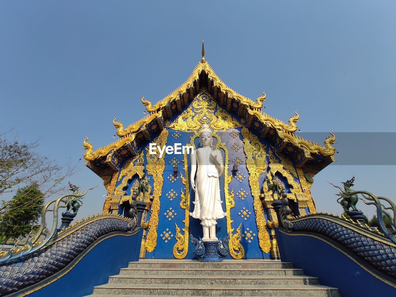 Low angle view of statue against temple building against clear sky