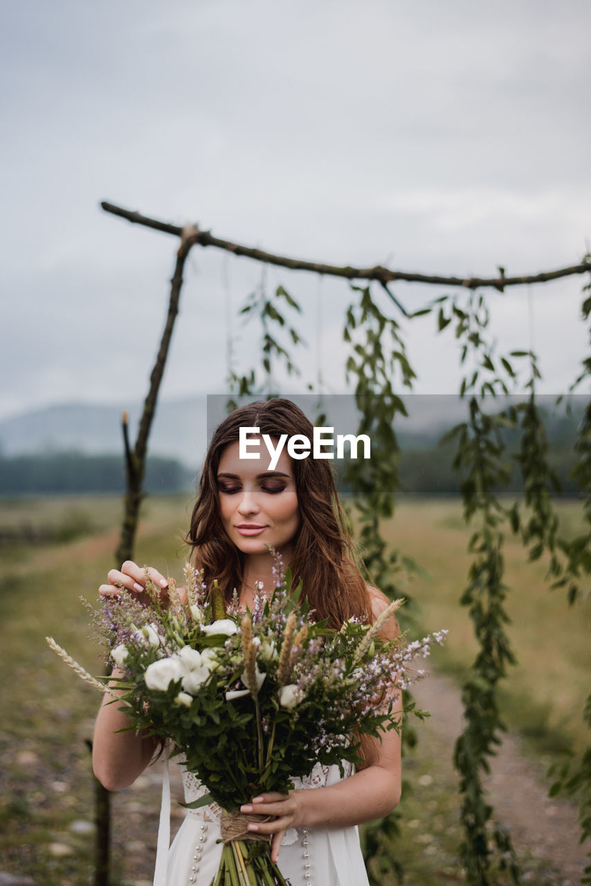 Bride holding bouquet while standing on field