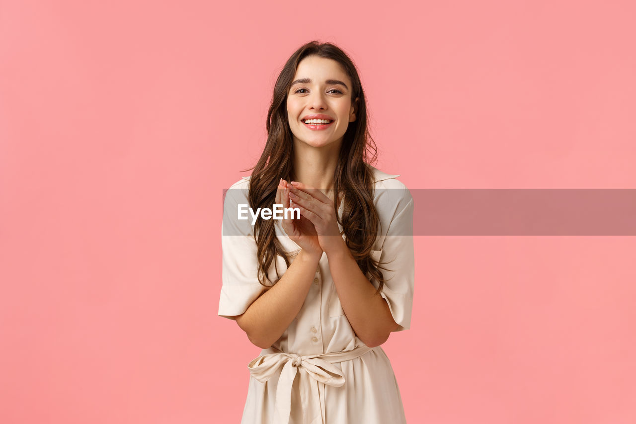 PORTRAIT OF SMILING YOUNG WOMAN AGAINST PINK BACKGROUND