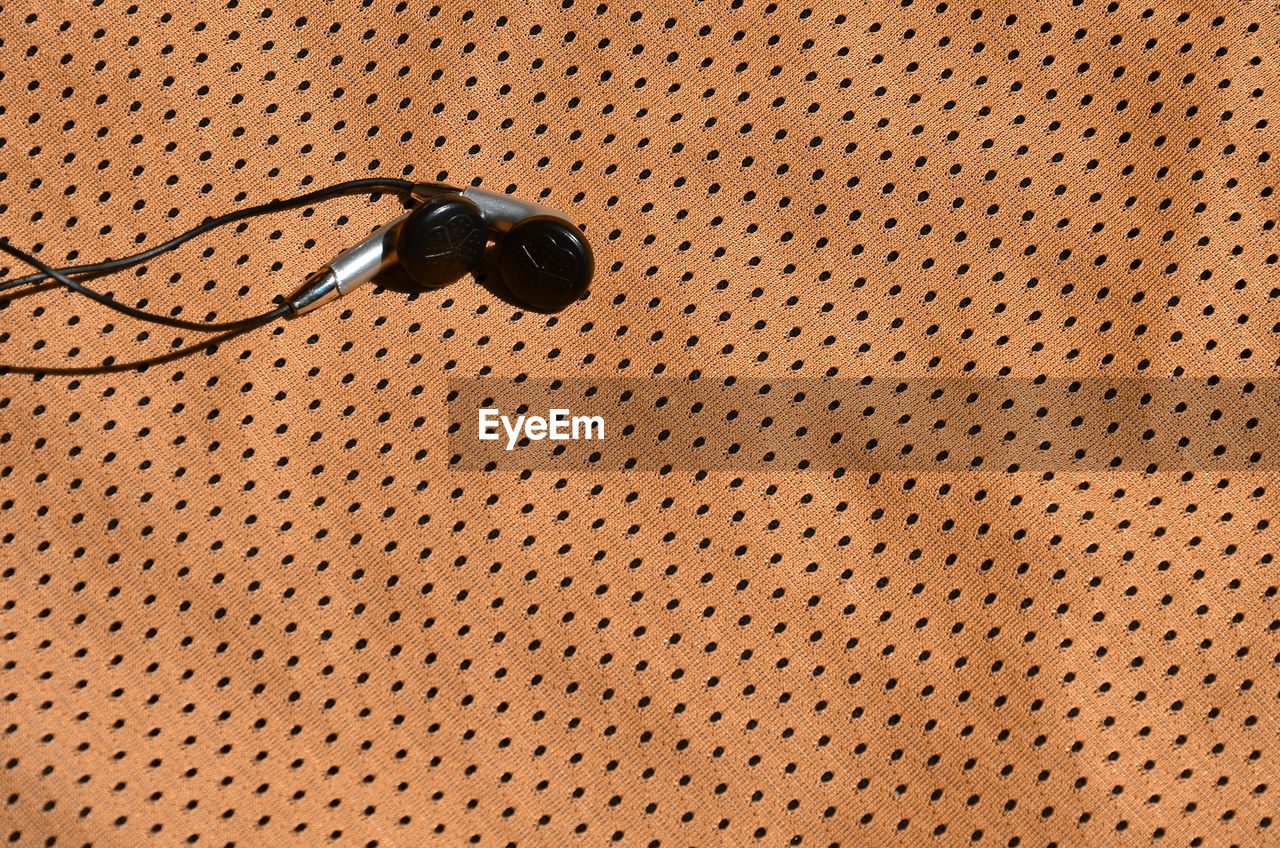 High angle view of in-ear headphones on textile