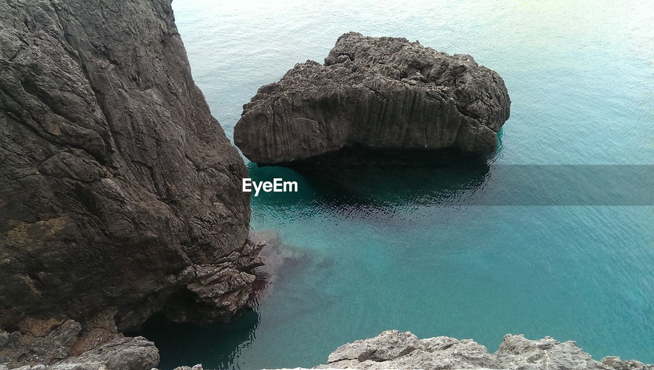 HIGH ANGLE VIEW OF ROCKS ON SEA SHORE