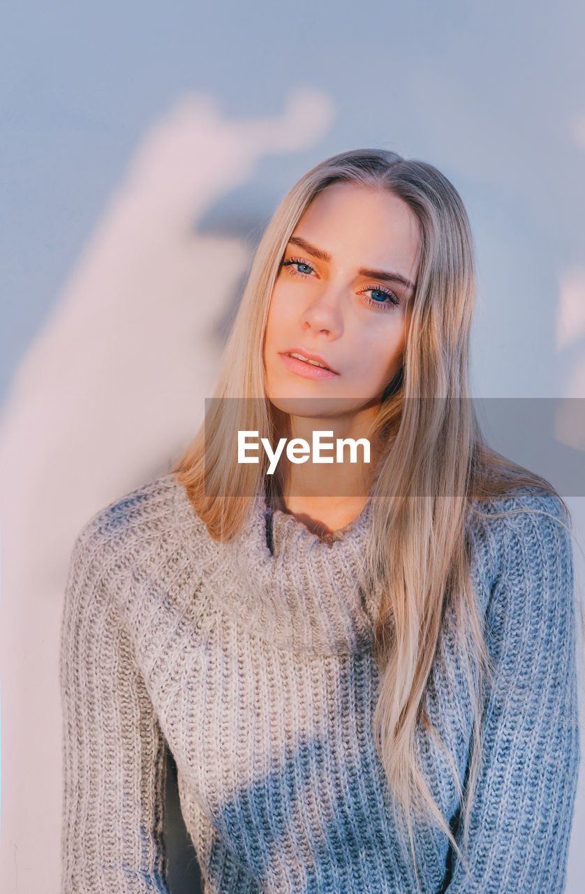 Portrait of beautiful young woman against wall