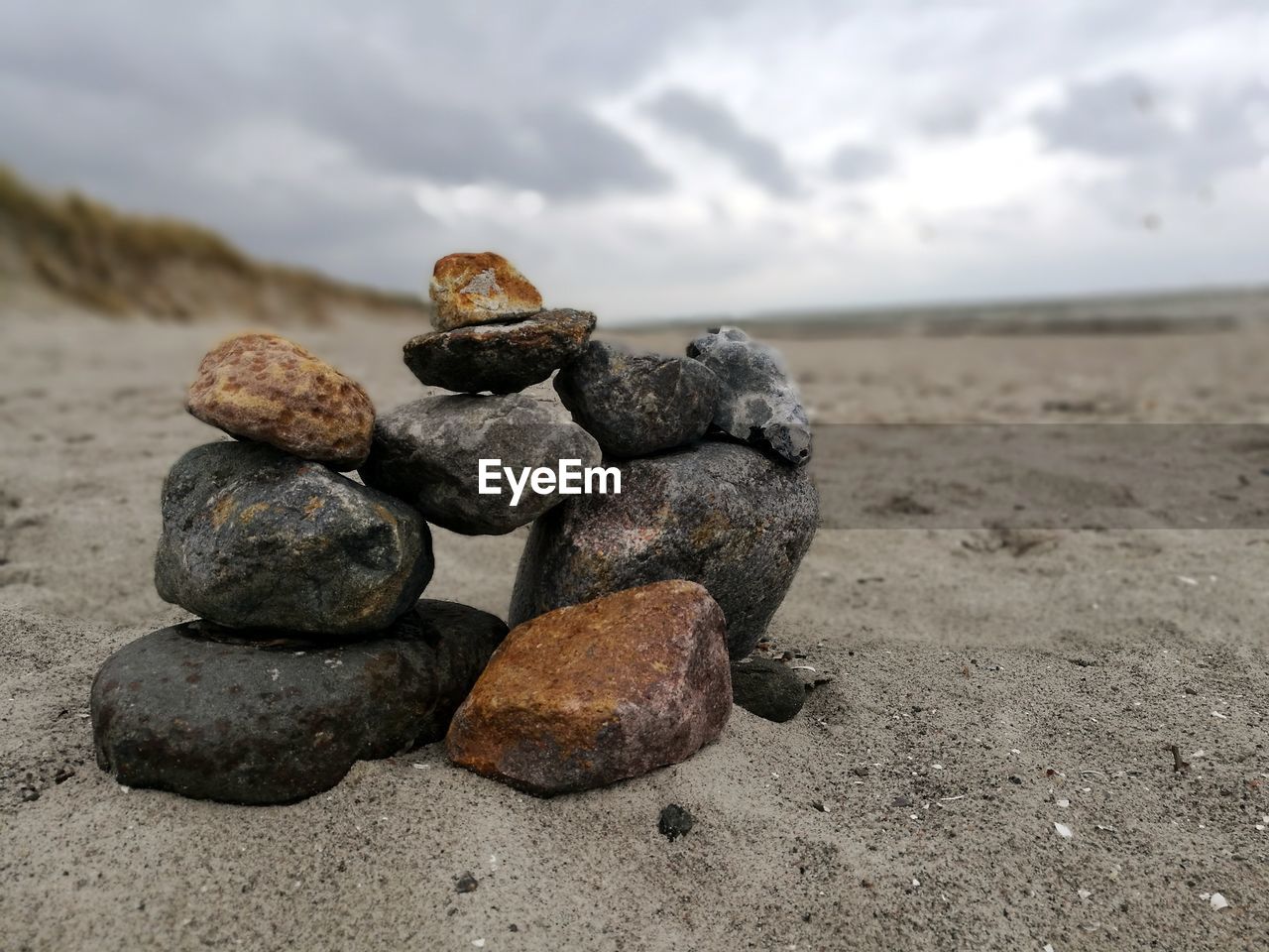 STACK OF PEBBLES ON SAND AT BEACH