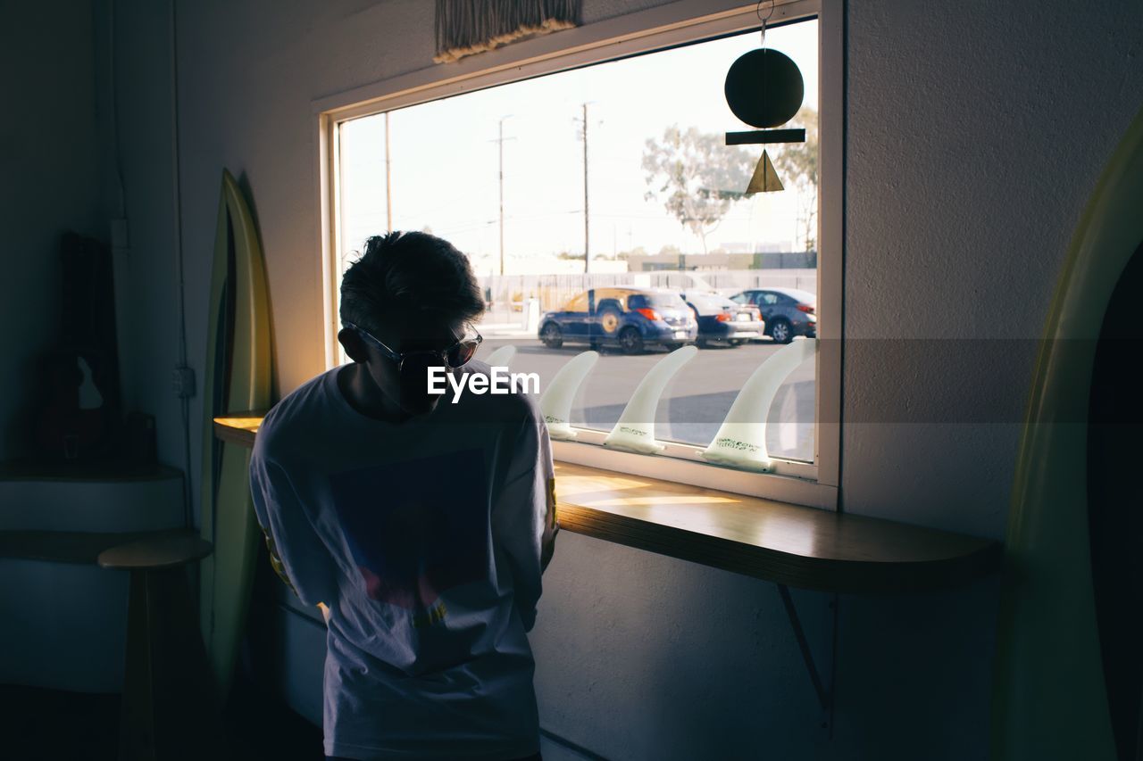 Man wearing sunglasses standing by window