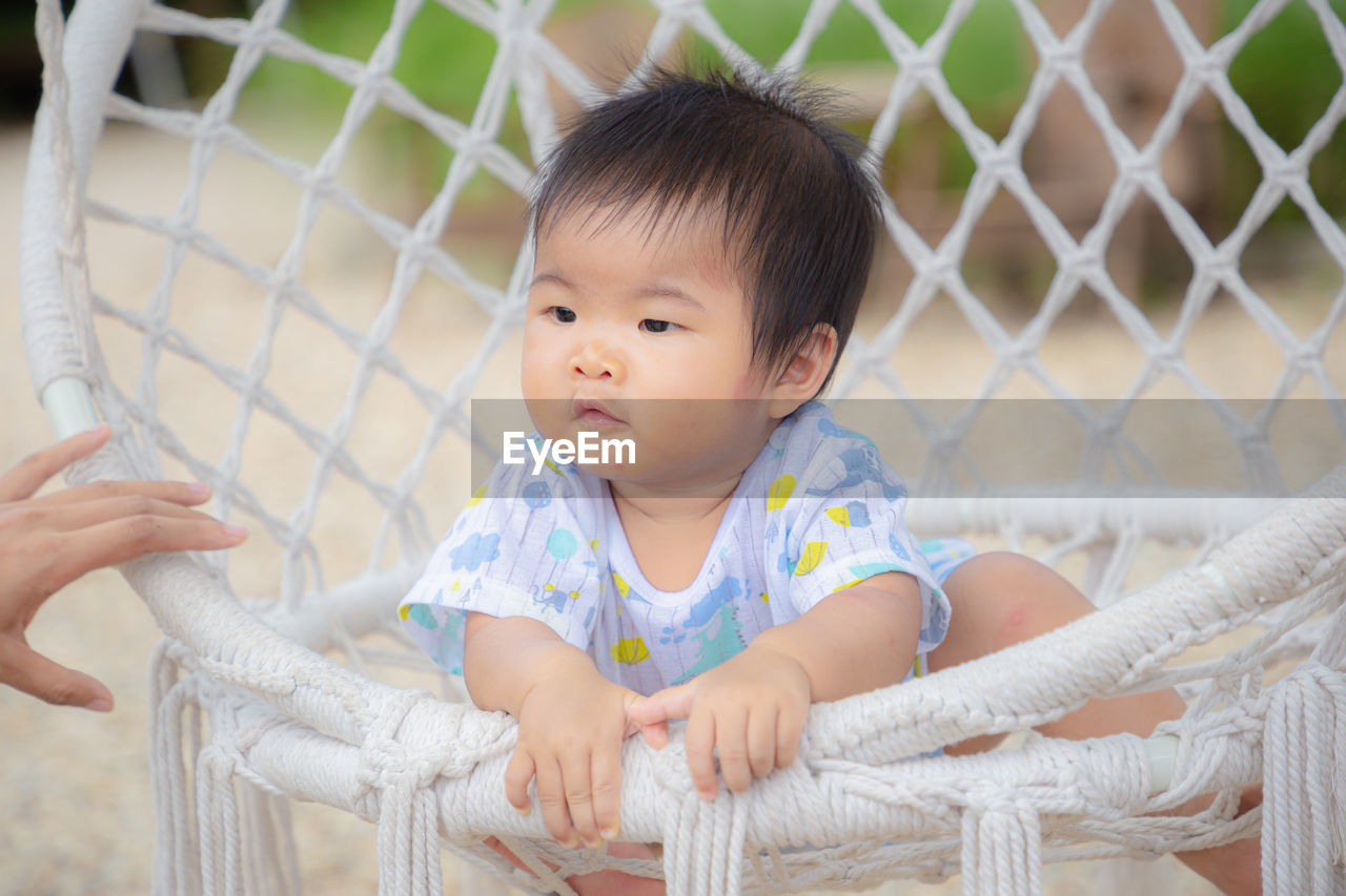 PORTRAIT OF CUTE BABY GIRL LOOKING THROUGH FENCE