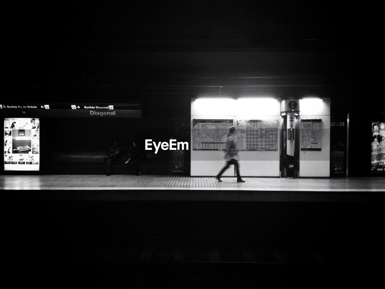 Side view of woman walking at railroad station during night
