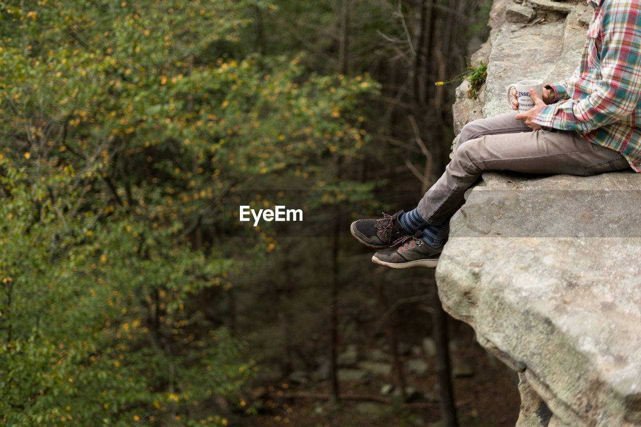 Low section of man sitting on rock