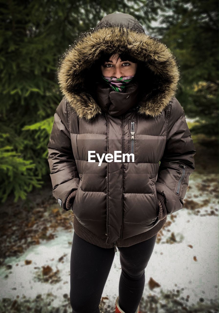 Portrait of young woman standing on snow covered land