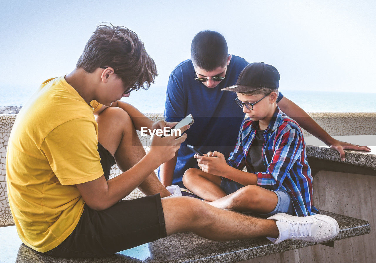 Teenagers friends using smartphone together. teens browsing social media online. boys watching video
