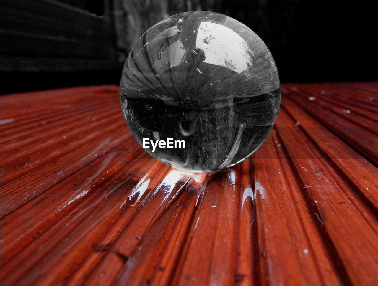 Close-up of crystal ball on wet wooden table