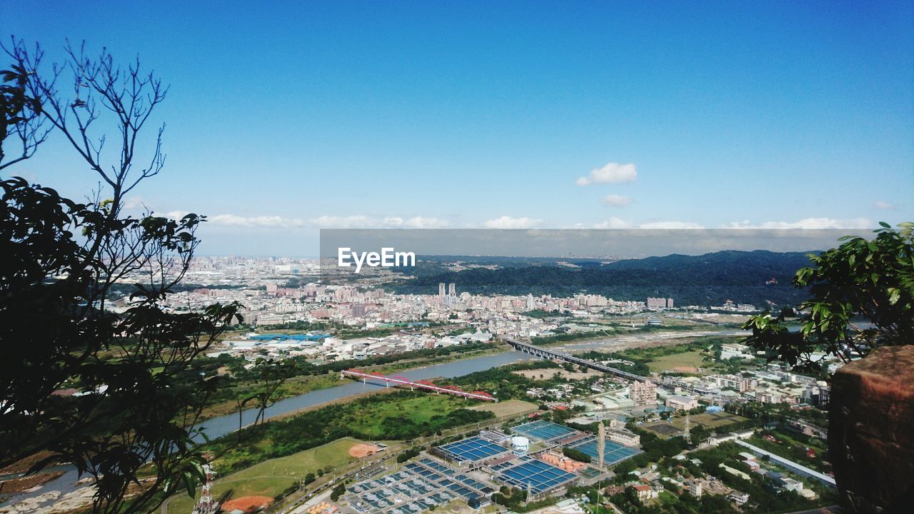 HIGH ANGLE VIEW OF CITYSCAPE BY SEA AGAINST SKY