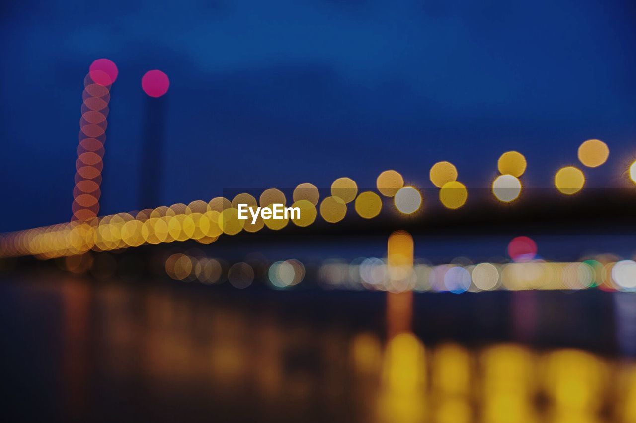 Defocused image of illuminated bridge over river at night