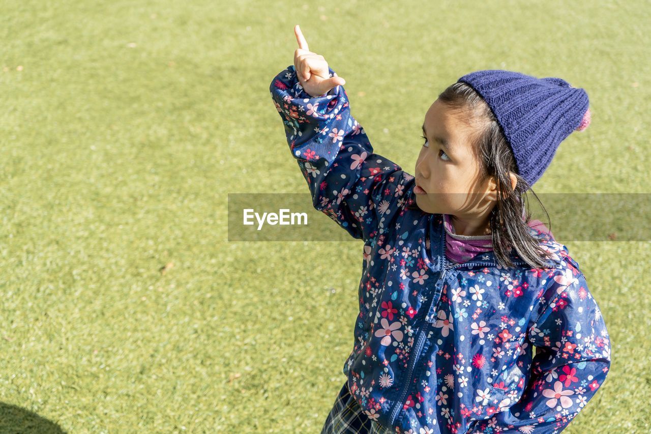 High angle view of girl pointing while standing on grass