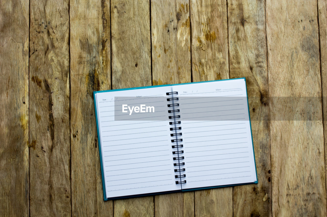 View of open notebook on wooden table