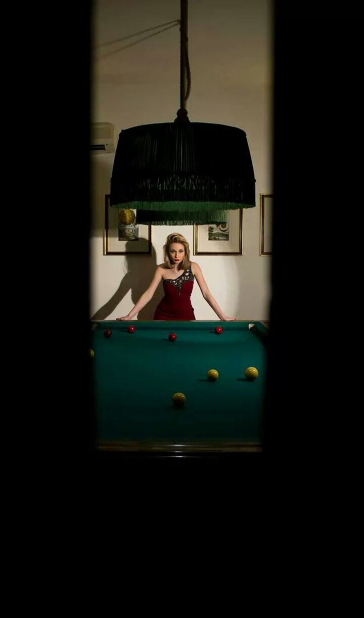 Portrait of young woman standing by pool table