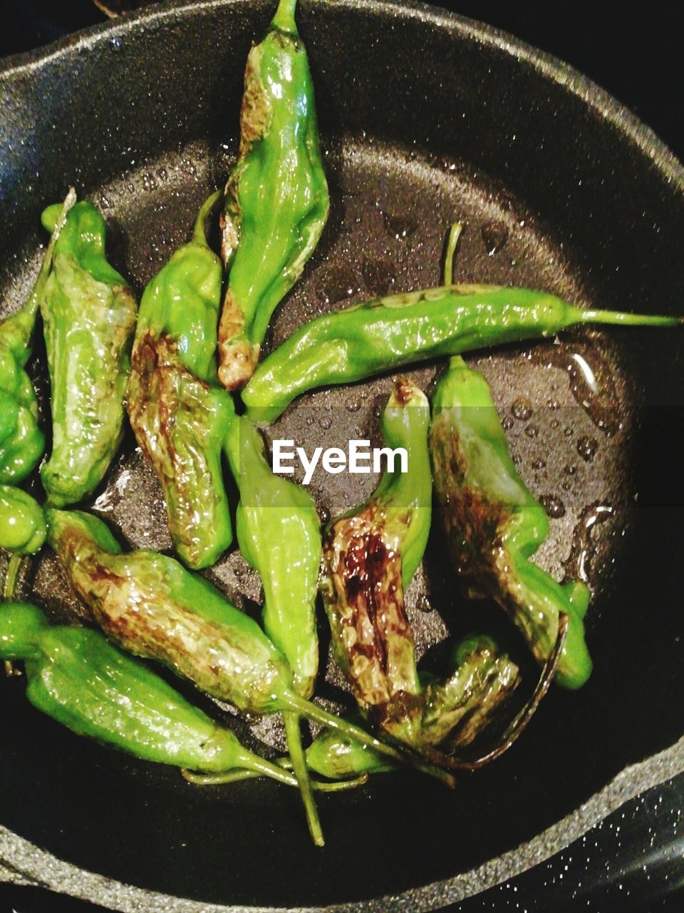 Green chilies on frying pan