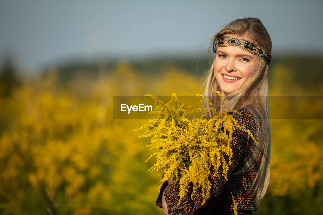 portrait of smiling young woman standing amidst plants