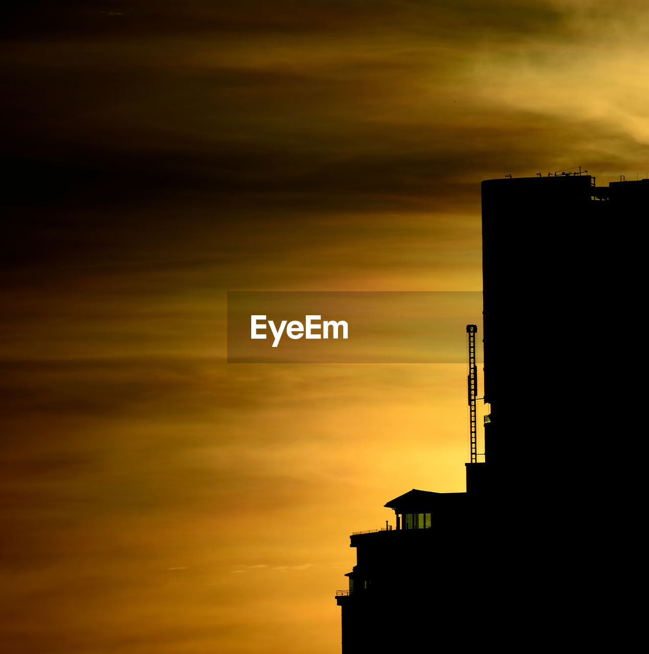 Low angle view of silhouette building against cloudy sky during sunset