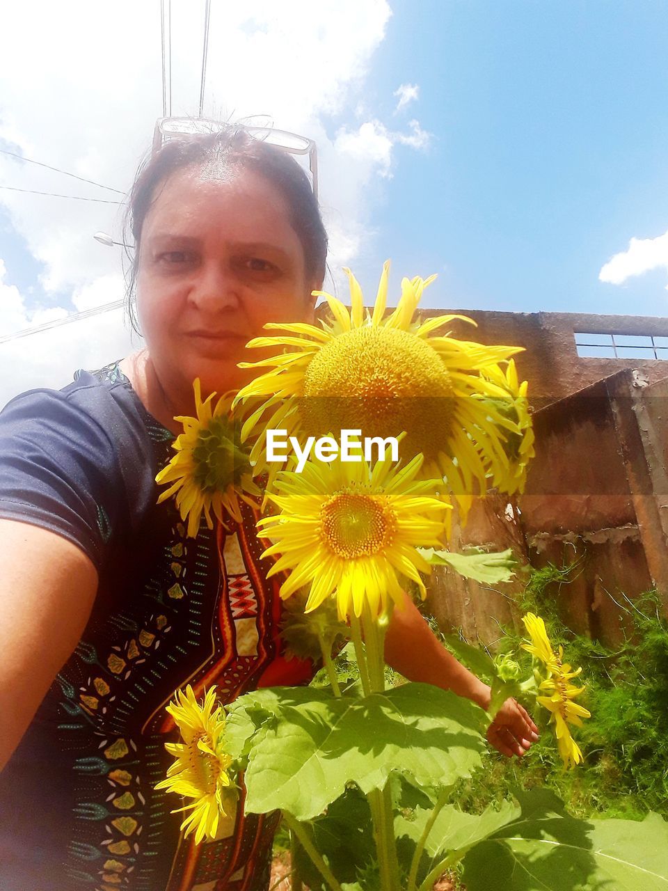 PORTRAIT OF WOMAN WITH YELLOW FLOWER IN GARDEN