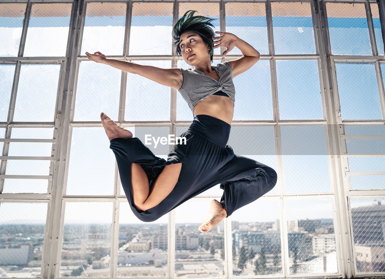 Full length of woman jumping against window