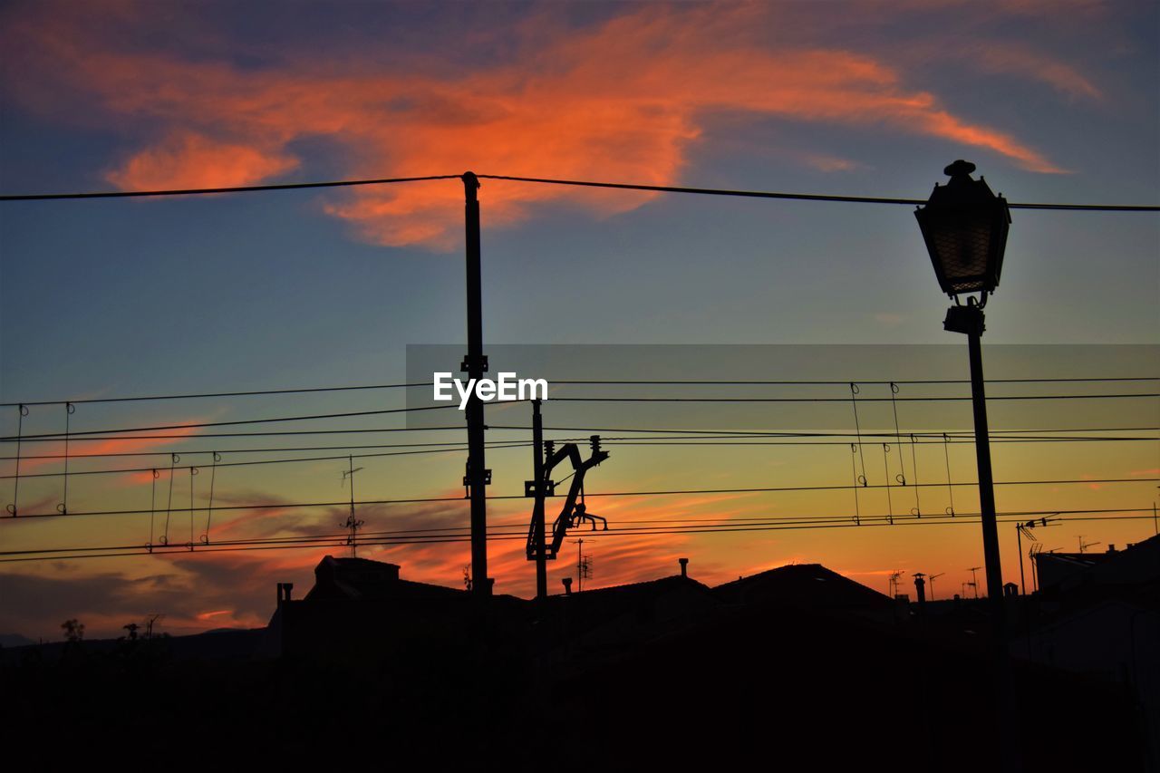 LOW ANGLE VIEW OF STREET LIGHTS AGAINST ORANGE SKY