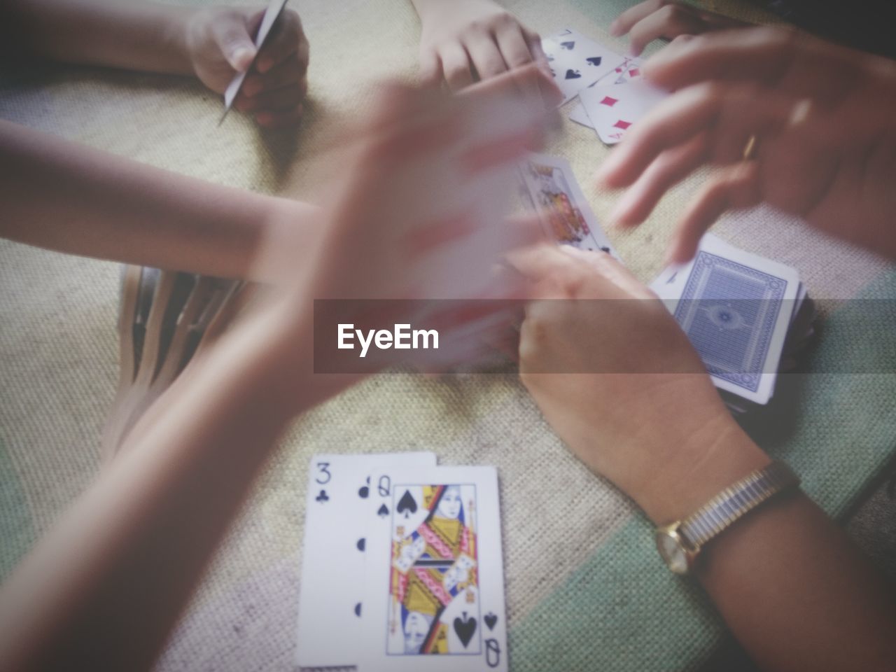 Cropped hands of friends playing cards at table