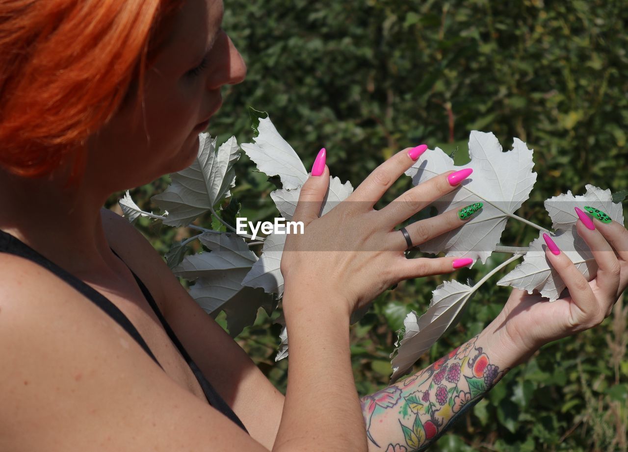 CLOSE-UP OF WOMAN HOLDING RED FLOWER