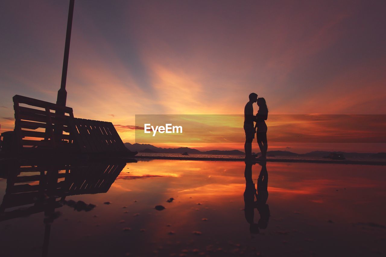 SILHOUETTE OF MAN ON LAKE AT SUNSET