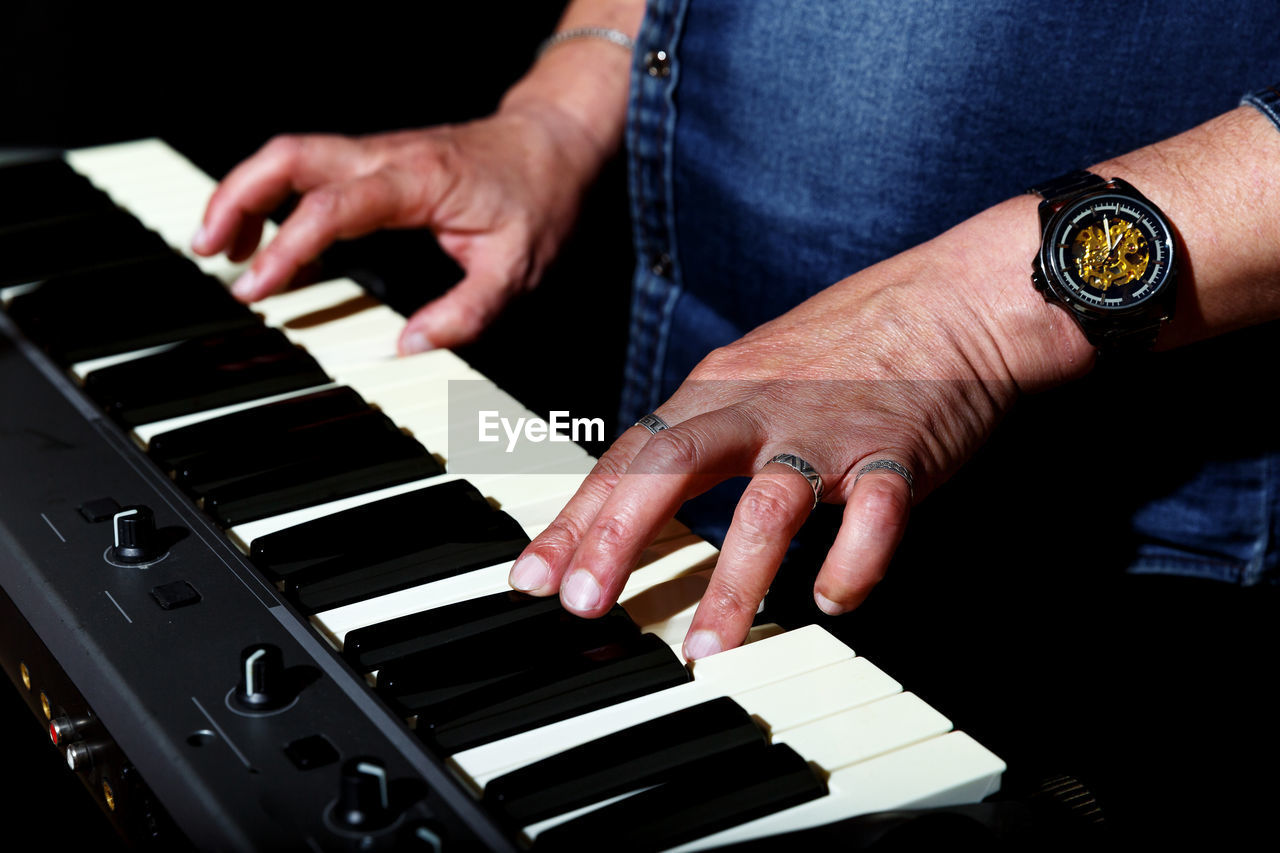 MIDSECTION OF MAN PLAYING PIANO IN MUSIC CONCERT