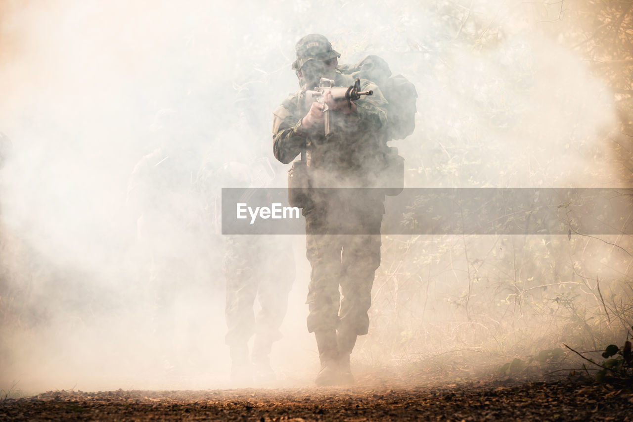 Army soldier shooting with rifle during foggy weather