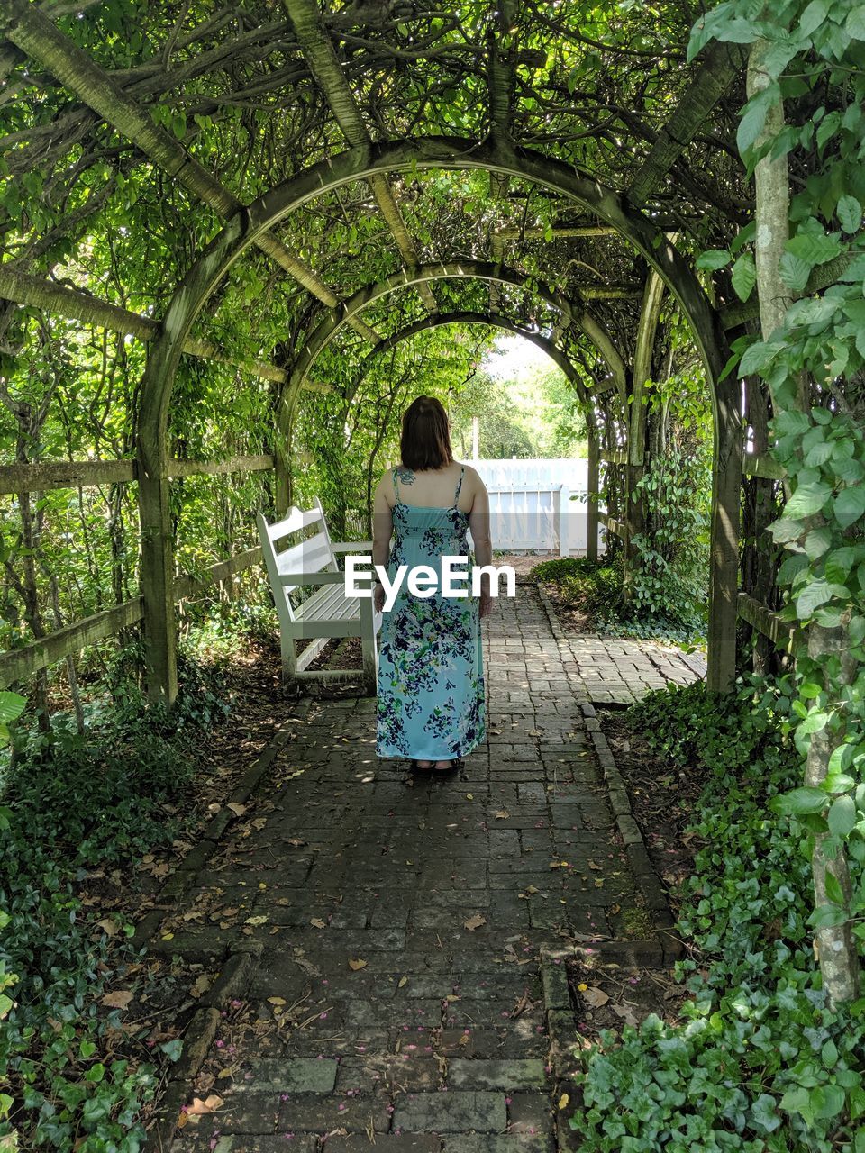 Rear view of woman standing below arch pergola