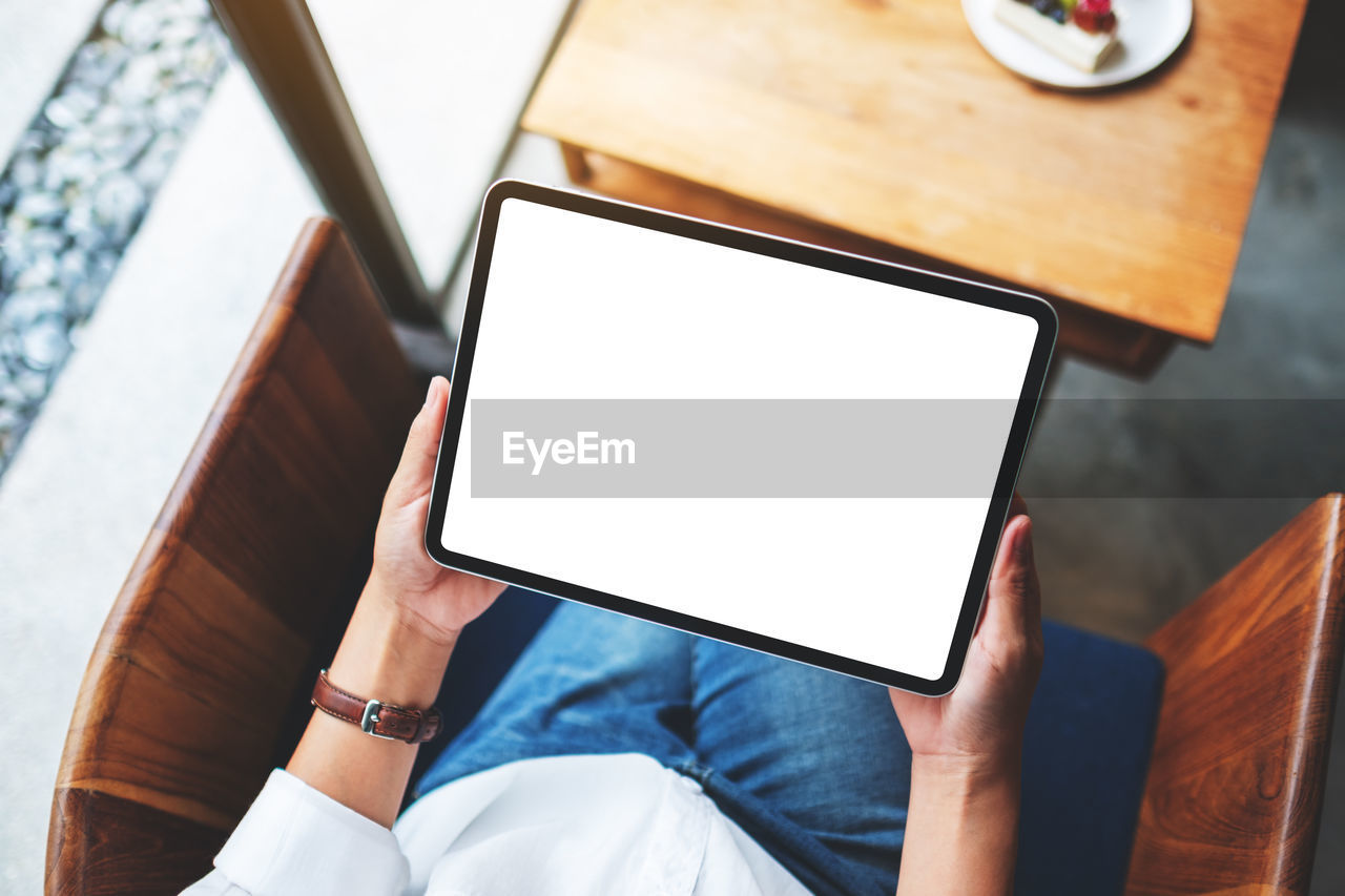 midsection of woman using digital tablet while sitting at home